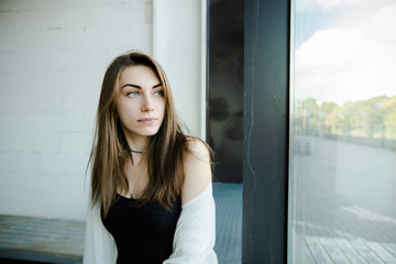 Portrait of trendy young caucasian woman posing near a window.