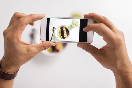 man photographing healthy breakfast by smartphone