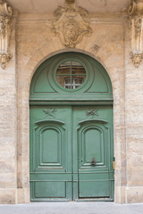 Fototapeta na wymiar Paris, beautiful wooden green door, girder with sculptures 