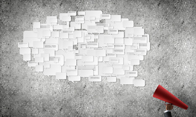 Hand of woman holding red paper trumpet against concrete background