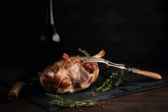 Freshly roasted lamb leg with herbs and bottle of red wine