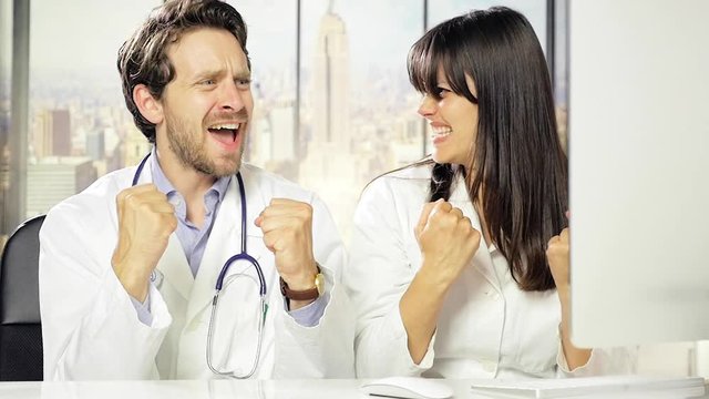 Male and female doctor celebrating success in office high five