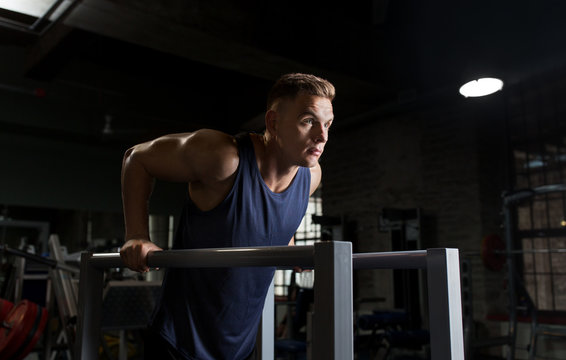 man doing triceps dip on parallel bars in gym