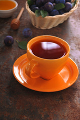 A cup of tea and plum on the table
