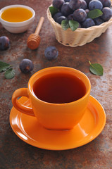 A cup of tea and plum on the table