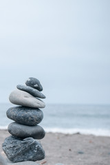 Fototapeta na wymiar Monochrome, Serene, Blue Stacked rocks on a California beach symbolizing Peace, Balance, Meditation, and Mindfulness with Room for Copy