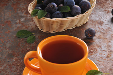 A cup of tea and plum on the table