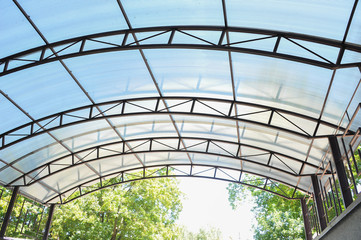 A canopy made of polycarbonate arc against the blue sky. Metal construction.
