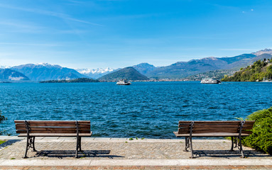 Landscape of Lake Maggiore with two benches on the shore in the foreground, Italy