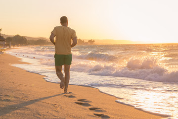 Man running on beach at sunset