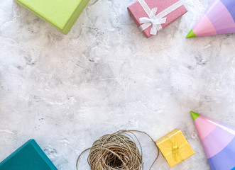 Preparing to celebration. Colored gift boxes and party hats on grey stone background top view copyspace