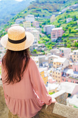 Fototapeta premium Beautiful woman with amazing view of the italian village in old street in Cinque Terre, Italy