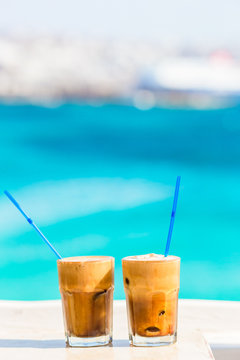 Frappe, ice coffee on the beach. Summer iced coffee frappuccino, frappe or latte in a tall glass background the sea in beach bar