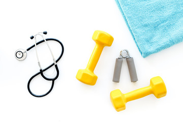Sport and health. Fitness. Dumbbells and stethoscope on white background top view