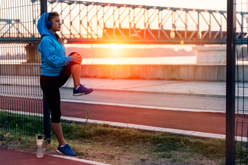Young sporty woman stretching outdoors in sunset