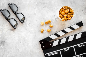 Watching film in the cinema. Clapperboard, glasses and popcorn on grey background top view copyspace