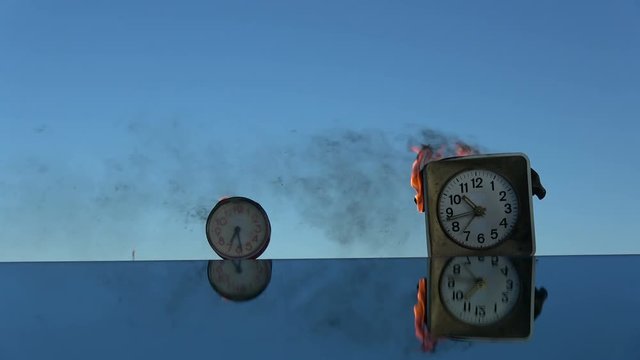 Time is a fire. Burning  old  alarm clocks on mirror in space. 