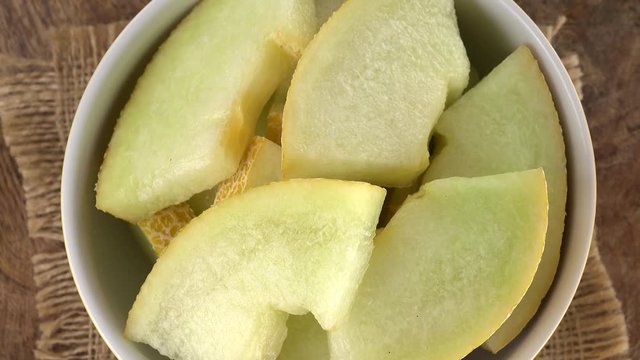 Honeydew Melon (chopped) rotating on a wooden plate (not loopable; 4K)