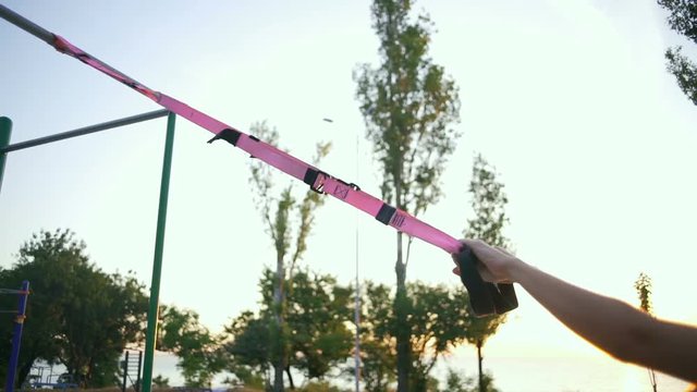 Young beautiful woman doing a high row trx exercise slow motion