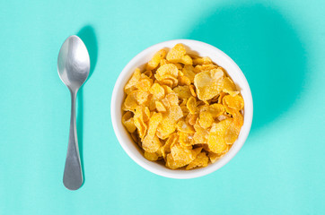 Corn flakes in a bowl with spoon for eating in the morning on green background,breakfast or meal