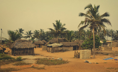 African village. Houses and barracks with thatched roof with palm trees in background. Rural lifestyle of West Africa. Traditional way of life in developing countries. Ghana, village near Atoko 