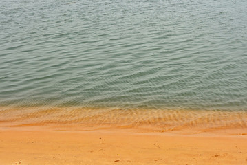 Sand beach background. Top view. Backdrop of yellow sand and rippled water. Travel & Vacation concept. Textured structure. Nice ocean coast. Wonderful landscape.