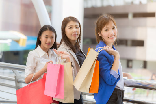 happy three women friends and shopping bags in they hand