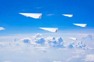 Paper plane flying against blue sky