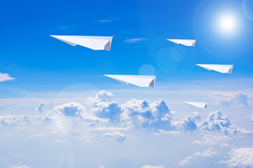 Naklejka na ściany i meble Paper plane flying against blue sky