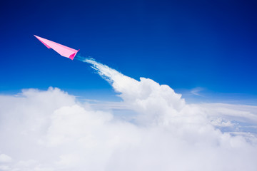 Naklejka na ściany i meble Pink paper plane flying against blue sky
