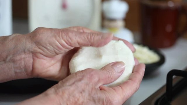Senior woman hands flattening the arepa dough with her hands to form the arepa typical shape