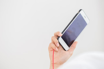 Hand holding smartphone with ear phone line,Copy space