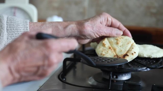 Senior woman hands turning the arepa over on the grill
