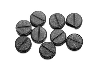 Activated charcoal pills on white background