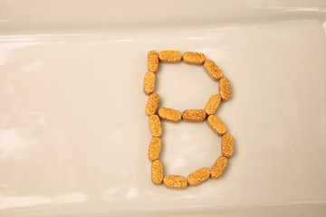 Gold gel capsule of vitamin B displayed on a white surface.
