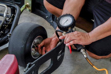 Checking tire pressure with tire gauge for drive