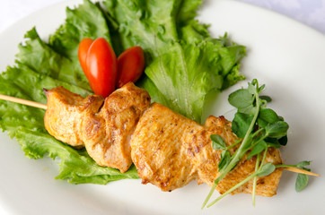 Chicken kebab on white plate, close up view