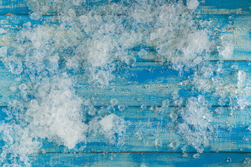 Crushed ice cubes on vintage blue wooden table. Top view