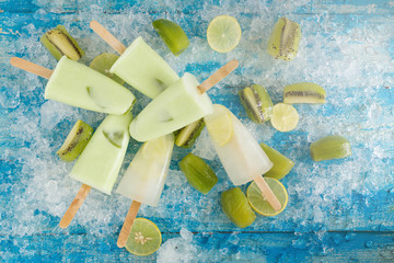 Crushed ice cubes and lemon, kiwi, homemade ice cream on vintage blue wooden table. Top view