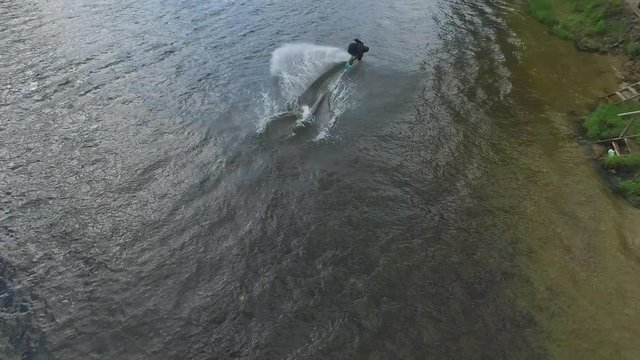 Flying over wakeboarding cable wake park HD aerial video. Wakeboarder doing jump tricks. Water extreme sport.