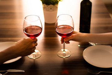 Romantic dinner. Two people each holding a glass of wine.