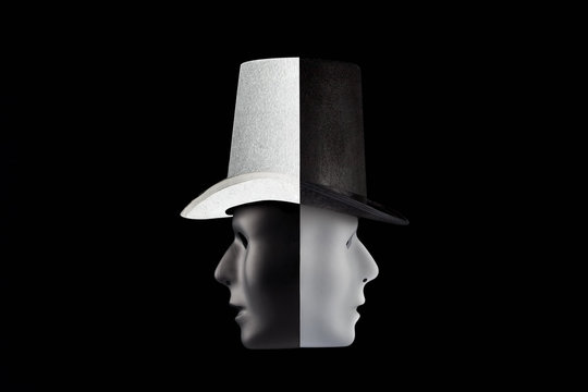 Black and white masks wearing top hat looking in opposite directions isolated on black background with copy space. Double talk and hypocricy concept