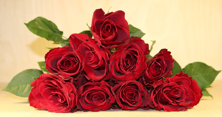 A bouquet of dark red roses with a white blank label on a wooden background