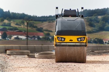 Road roller working on the new road construction site. Construction machine on an empty...