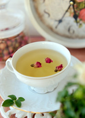 Cup of healthy green tea with dried roses