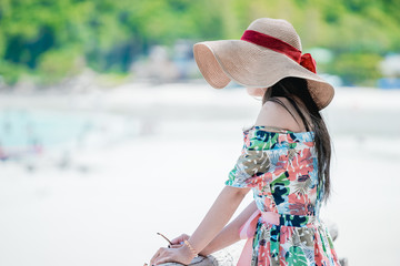 Young woman wearing Hawaiian with hat and sunglasses is happy when they go to the beach for a holiday.