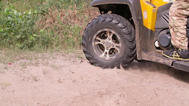 Man driving quad bike HD slow-motion video. Close-up of wheels. All-terrain vehicle riding ATV in forest. Four-wheeler quadricycle transport and extreme sport.