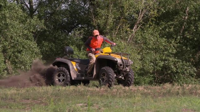 Man driving quad bike HD slow-motion video. All-terrain vehicle riding ATV on turn in forest. Four-wheeler quadricycle transport and extreme sport.