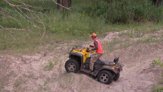Man driving quad bike HD slow-motion video. All-terrain vehicle riding ATV in forest. Four-wheeler quadricycle transport and extreme sport.