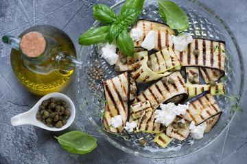 Barbecued eggplant and zucchini slices with olive oil, capers and cheese, top view, horizontal shot